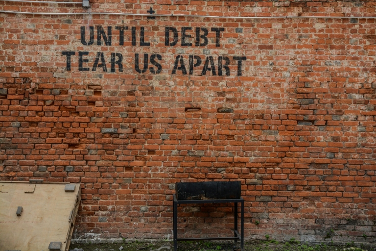 Brick wall with the phrase "Until debt tear us apart"