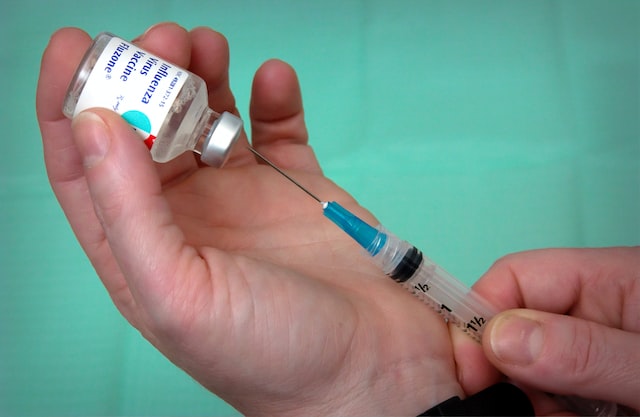 Person preparing a syringe from a vial of influenza vaccine